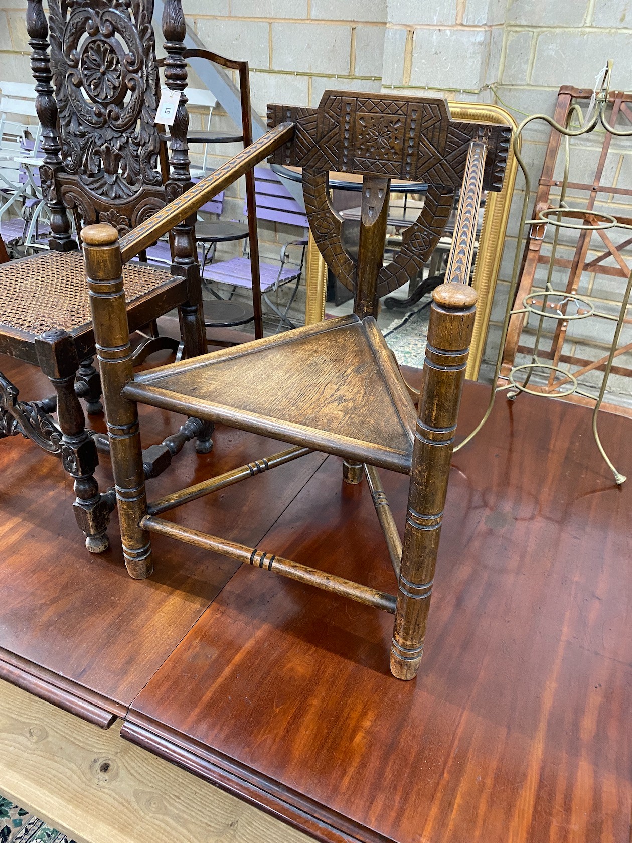 A Carolean style carved oak cane seat highback dining chair together with a chip carved oak chair with triangular seat